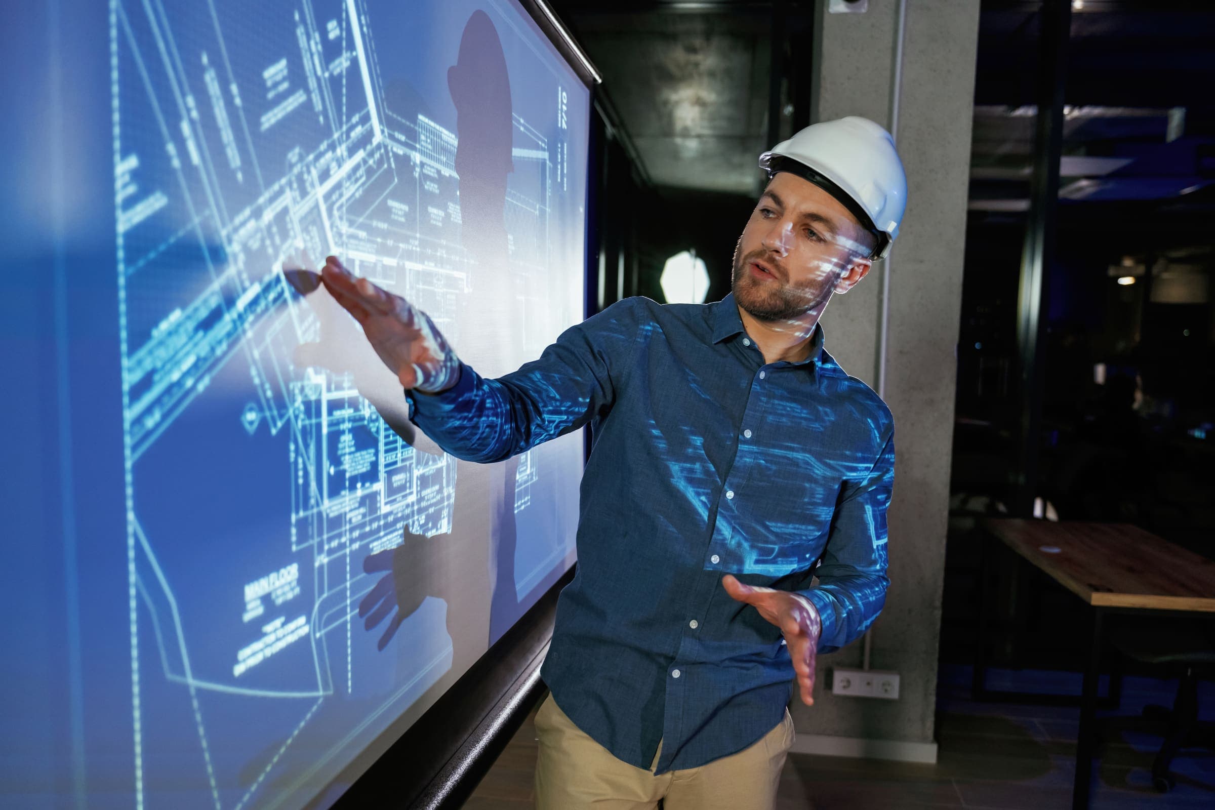 Engineer wearing a hard hat reviewing a digital building blueprint