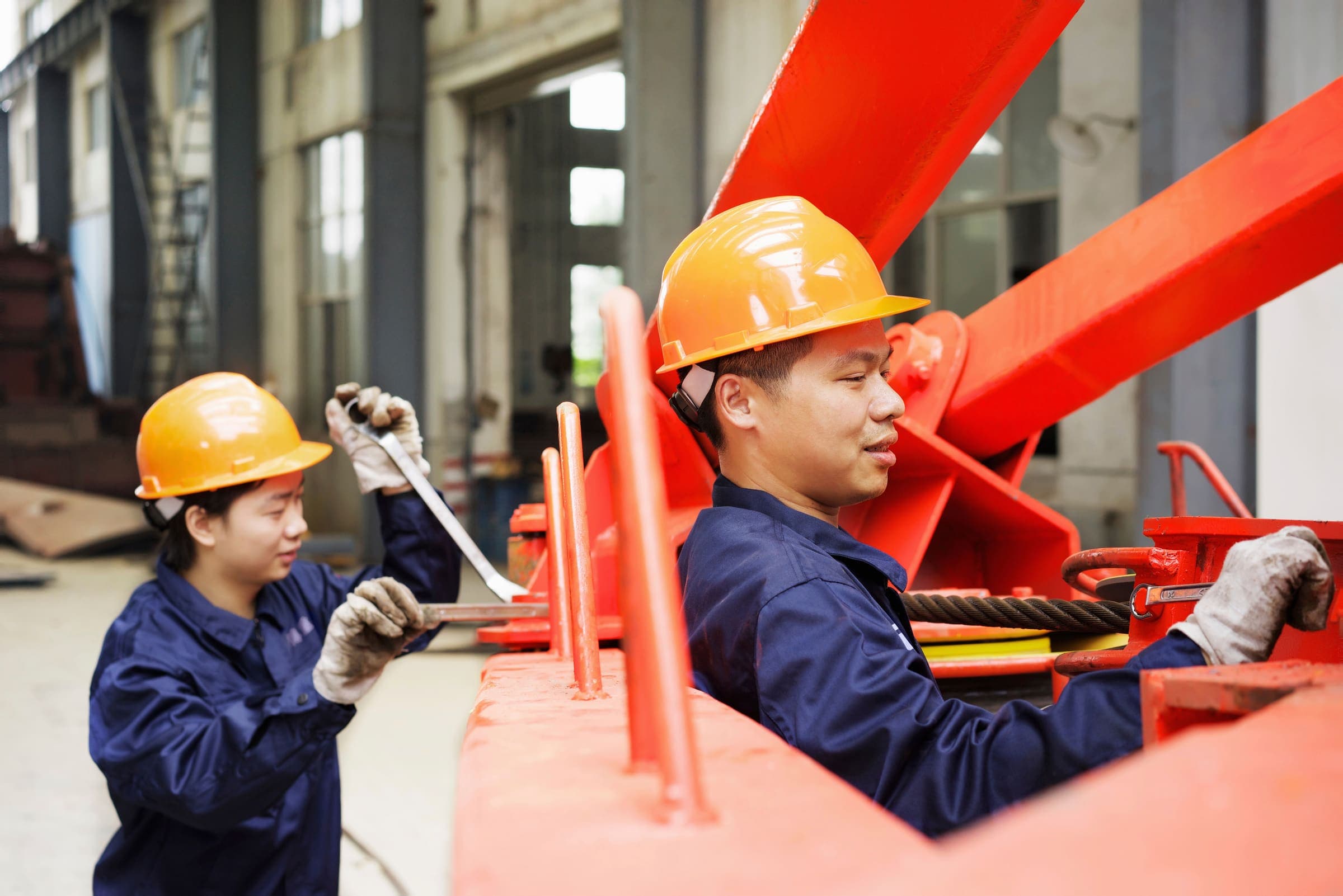 Workers operating crane equipment in a manufacturing and logistics facility
