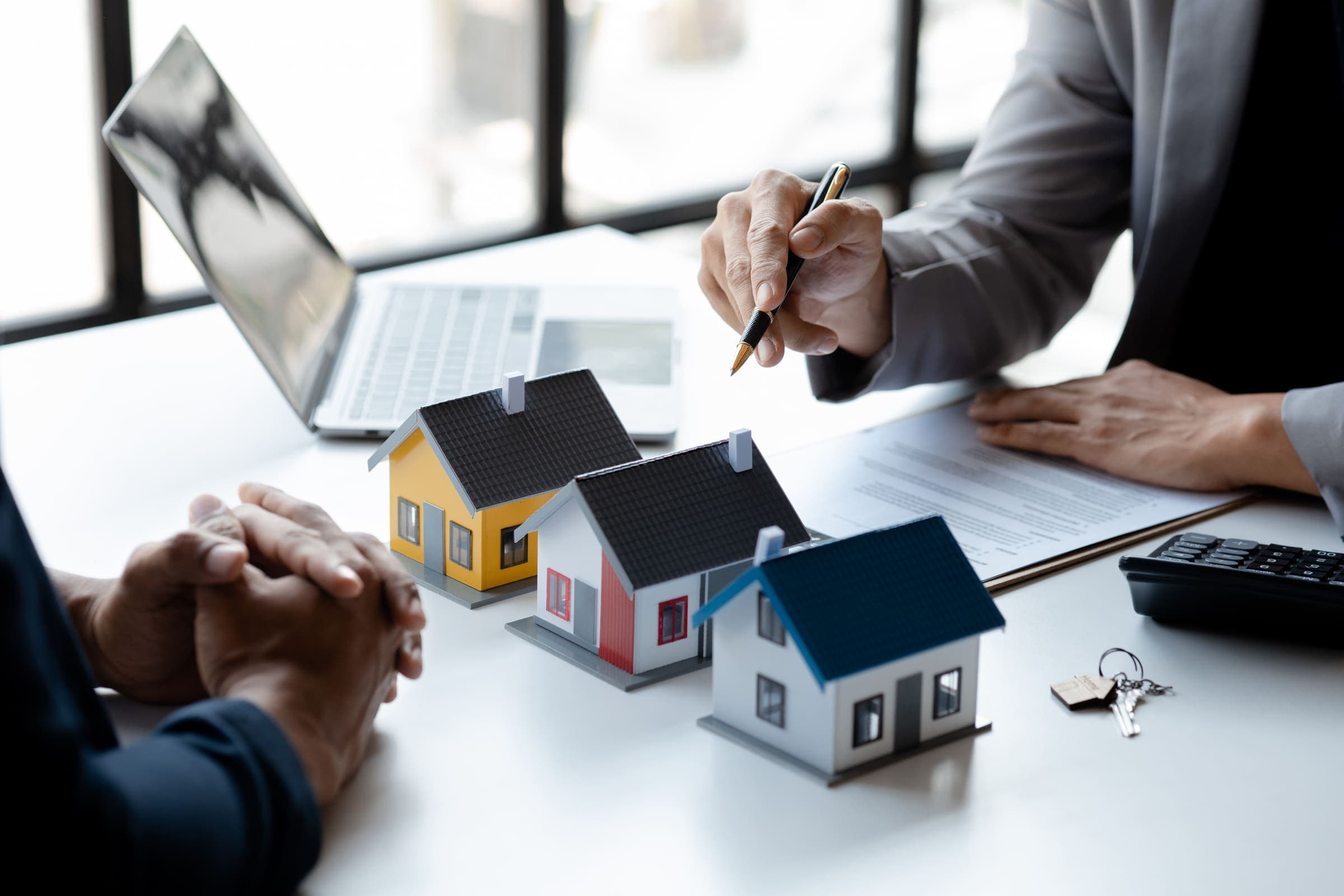 Real estate agent reviewing a contract beside house models and keys